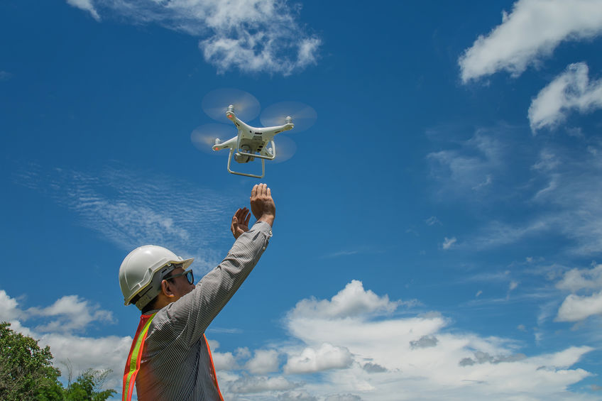 Young engineer use drones outdoor with beautiful sky with clouds, the man holding Drone